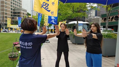 图5:来自德国的凯瑟琳·彼得森(Katherine Peterson)和莎拉·柏拉姆(Shara Bayram)正在学习法轮功的炼功动作。