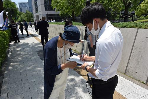 图5:川村先生在征签表格上签名支持法轮功学员反迫害活动