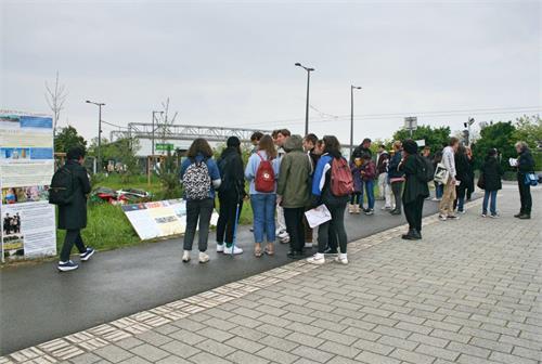 '图5~9:过往行人,有的阅读真相展板,有的向法轮功学员了解真相。'