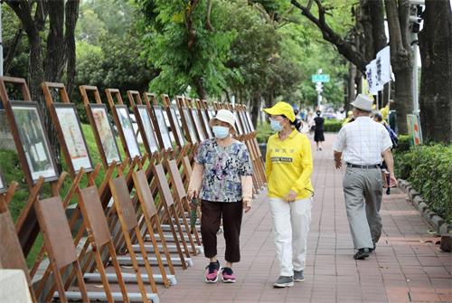 图3: 李姓学员陪着对大法有误解的老太太,边走边看展板,经过学员细心讲真相之后,老太太心中豁然开朗,解开心中的误解。