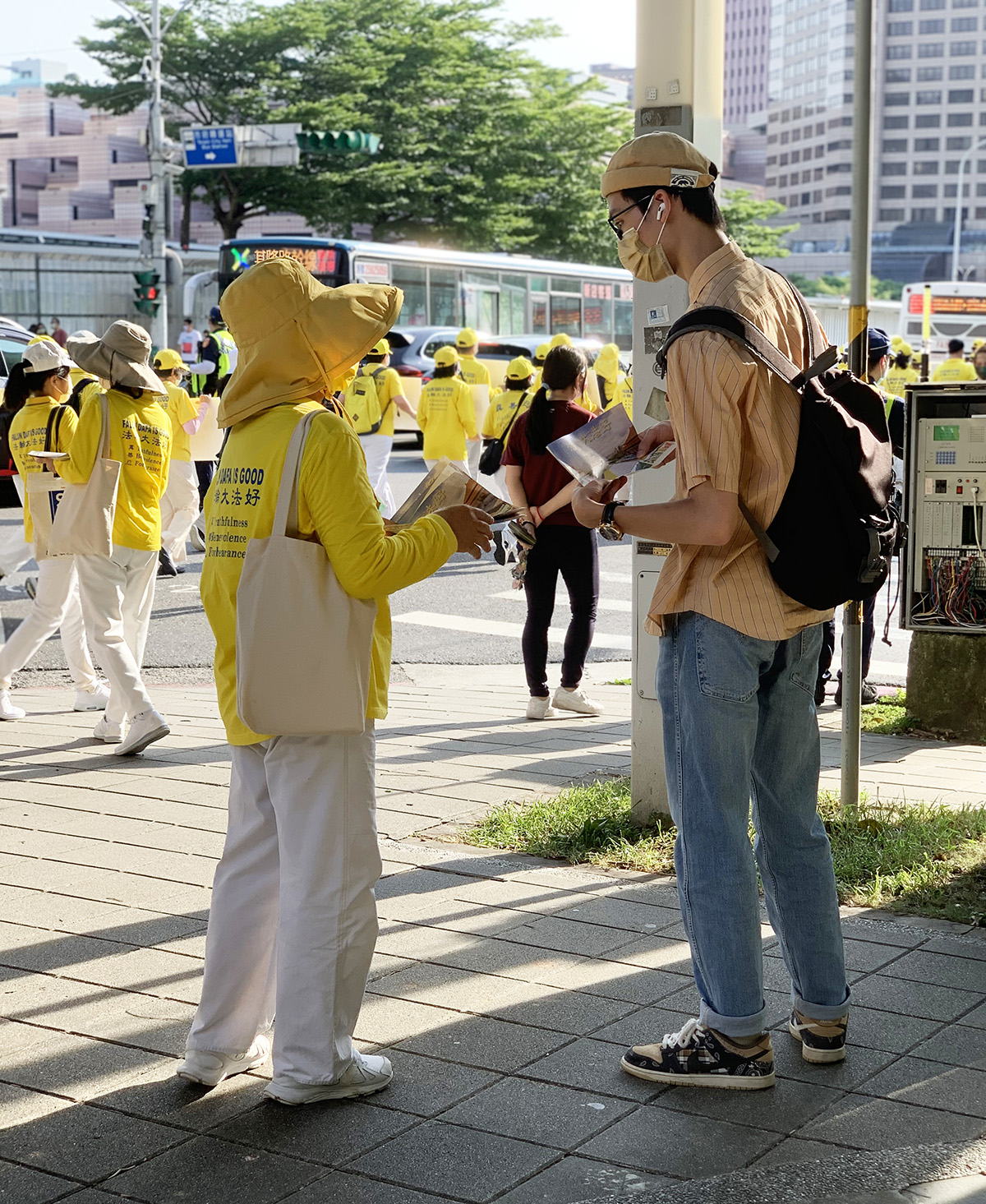 图15~16:学员向观看游行队伍行进的民众派发资料及讲真相。