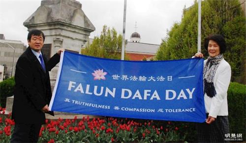 '图1:在加拿大升旗仪式上,王金菊(右)和同伴展示“世界法轮大法日”旗帜。'