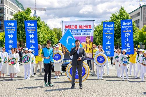 '图11:世维大会主席多里坤·艾沙(Dolkun Isa)委派柏林办公室主任海玉儿·库尔班(Haiyuer Kuerban)参加了法轮功学员在勃兰登堡门的集会。'