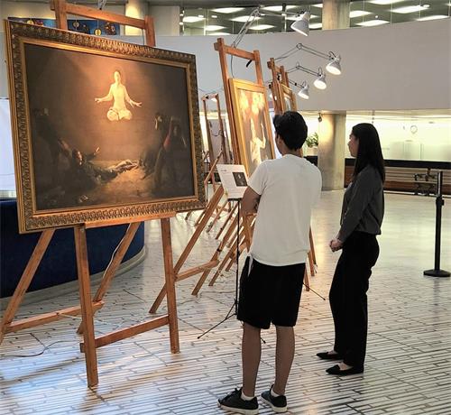 图11:雷(Ray左)在认真观赏画展。他表示很难想象在中共的统治下,有多少人面临着残酷的迫害。