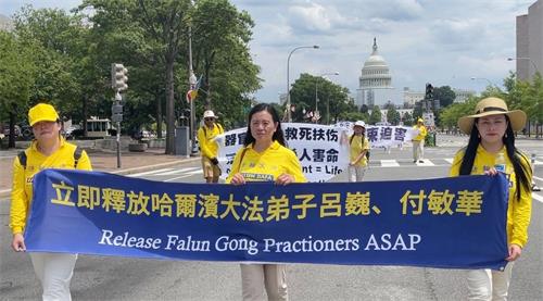 '图:2022年7月21日,美国首都华盛顿及周边地区的部份法轮功学员举行反迫害游行,吕娜打出 “立即释放哈尔滨大法弟子吕巍” 条幅。'