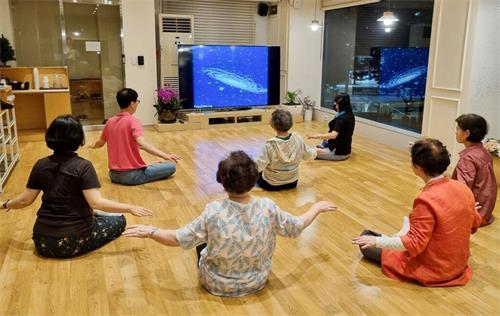 '图2:参加六月份法轮大法九天班(晚间班)的新学员们正在学习法轮大法第五套功法--神通加持法。'