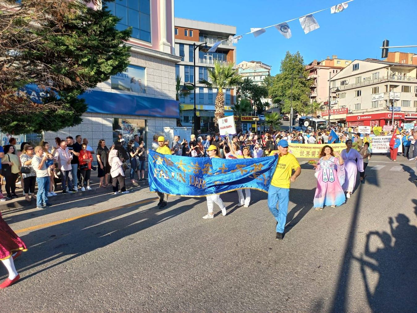 '图2:七月二十一日,土耳其法轮功学员参加“爱、友谊与和平”国际文化艺术节的游行,受到两旁观众的欢迎,他们有的跟学员招手,有的鼓掌喝彩。'