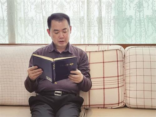 '图1:金永标正在阅读法轮大法的书籍《转法轮》。他回想第一次看《转法轮》的感觉,说:“越看越觉得精力充沛”。'