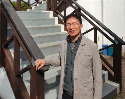图2:崔成基站在一公园咖啡店前。他每到周末,都会在公园入口处,向行人分发法轮功真相传单。