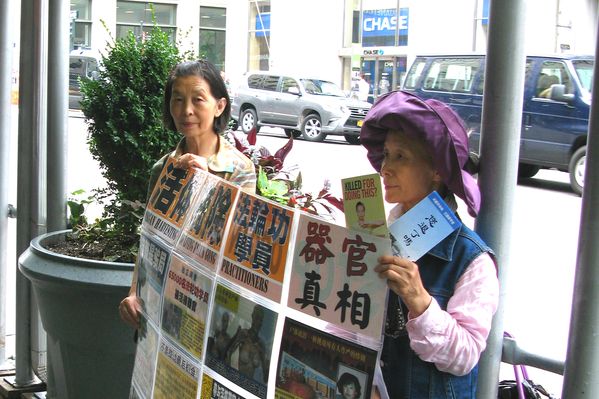 图3:2015年7月15日,纽约曼哈顿帝国大厦门前,从大陆流亡海外的法轮功学员葛荣贞(左)和李敏(右)手举真相展板。