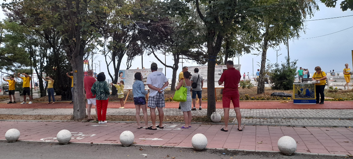 图4:二零二二年八月十五日,法轮功学员来到南伊芙利亚(Eforie Sud)海边设立真相点。不少游客驻足观看大型真相展板,有的和学员交谈,了解真相