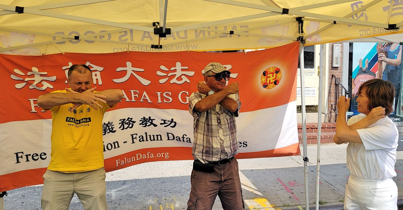 '图5:亨利(中)看到法轮功的展位,就走入帐篷,与学员一起炼功。'