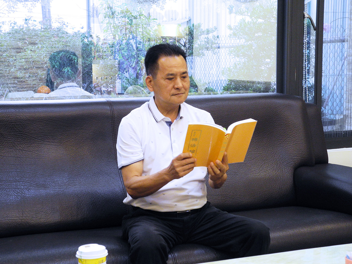 图1:文斌端坐恭敬阅读《转法轮》。