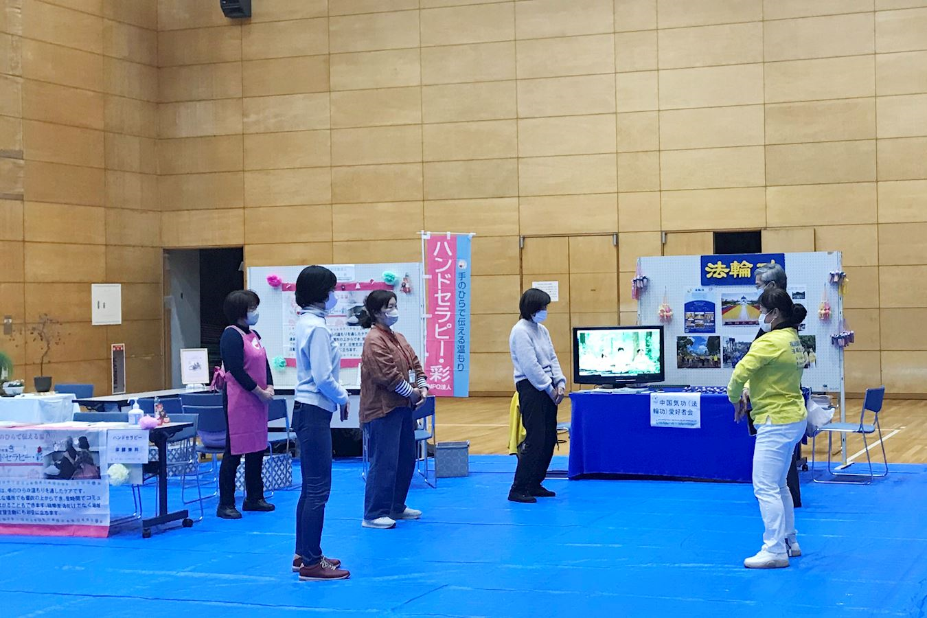 '图4:人们学炼法轮功的功法动作,连旁边展位的工作人员也一起加入了学功的行列。'