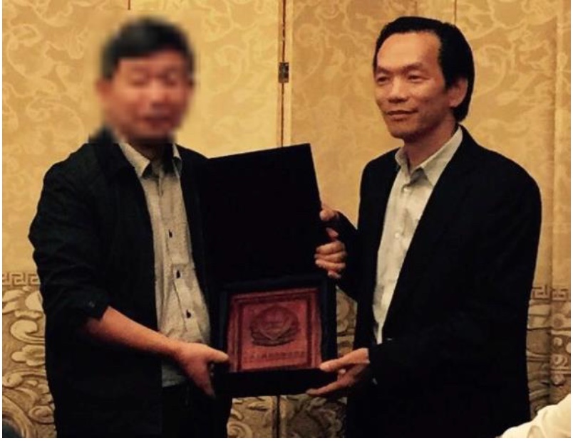 图3:二零一五年习近平访美后卢建旺(右)收到中共公安部颁发的一块牌匾。(起诉书截图)