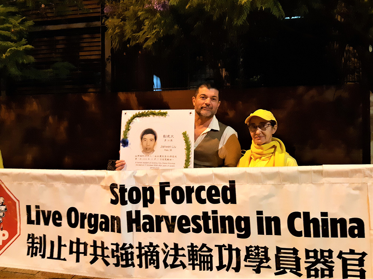 图6:卡鲁索举起受害者花环遗照,拍照留念。