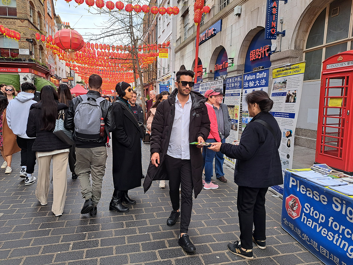 图2:唐人街法轮功展位上,人们驻足了解真相,并接过真相传单