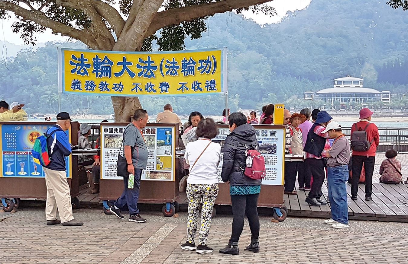 '图2~3:日月潭伊达劭早期众多大陆游客驻足围观在展版前观看真相展版,了解真相。'