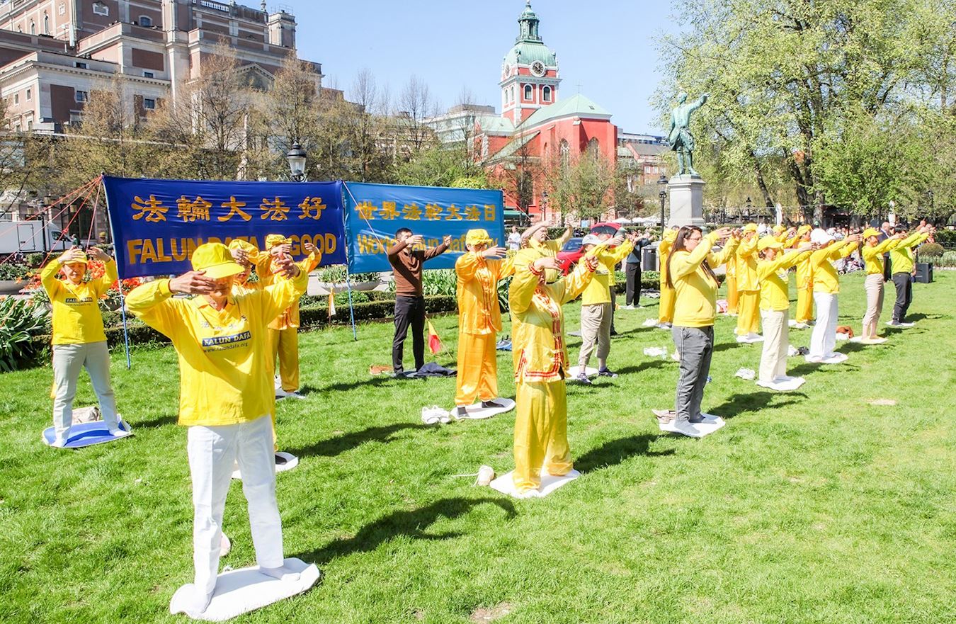 '图1~2:二零二三年五月十三日,法轮功学员在斯德哥尔摩皇家花园与民众共庆世界法轮大法日,学员们在集体炼功,展示五套功法。'
