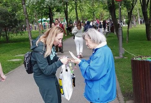 '图7:二零二三年五月六日,一名法轮大法学员在德鲁穆尔·塔贝雷公园门口发放真相资料和莲花。'