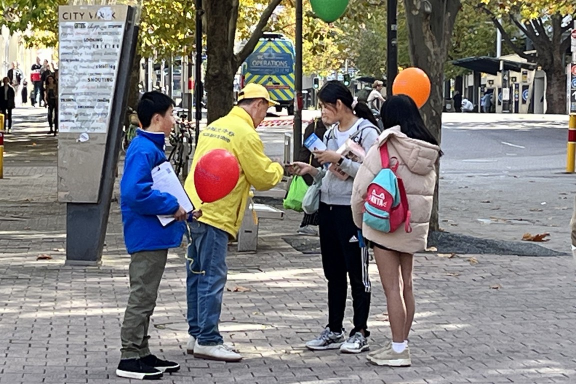 图2:法轮功学员向路人发真相资料,征签、赠送气球和莲花等。