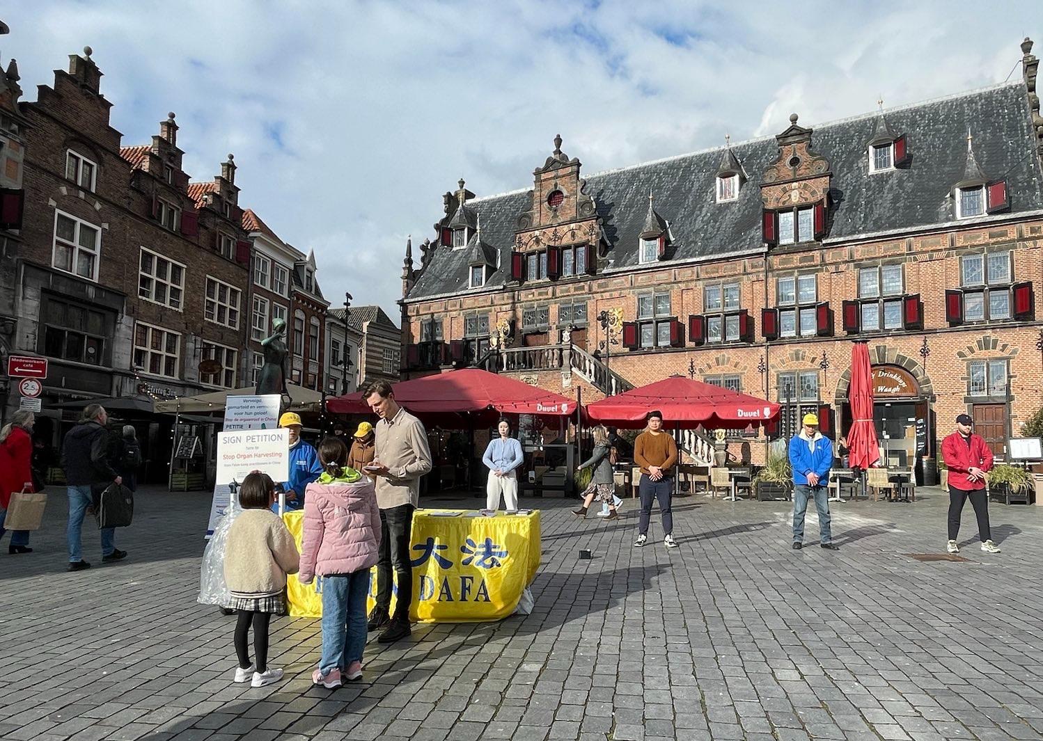 图1:法轮功学员在荷兰奈梅亨市(Nijmegen)设立真相点,民众前来了解仍在进行的中共对法轮功的迫害真相。