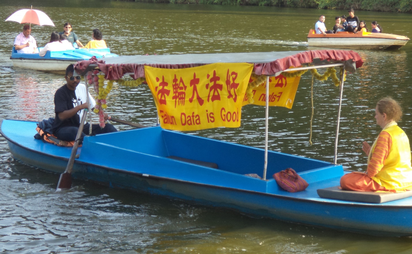 图14:法轮功学员克里斯蒂娜在湖上乘船,船上悬挂着“法轮大法好”的横幅