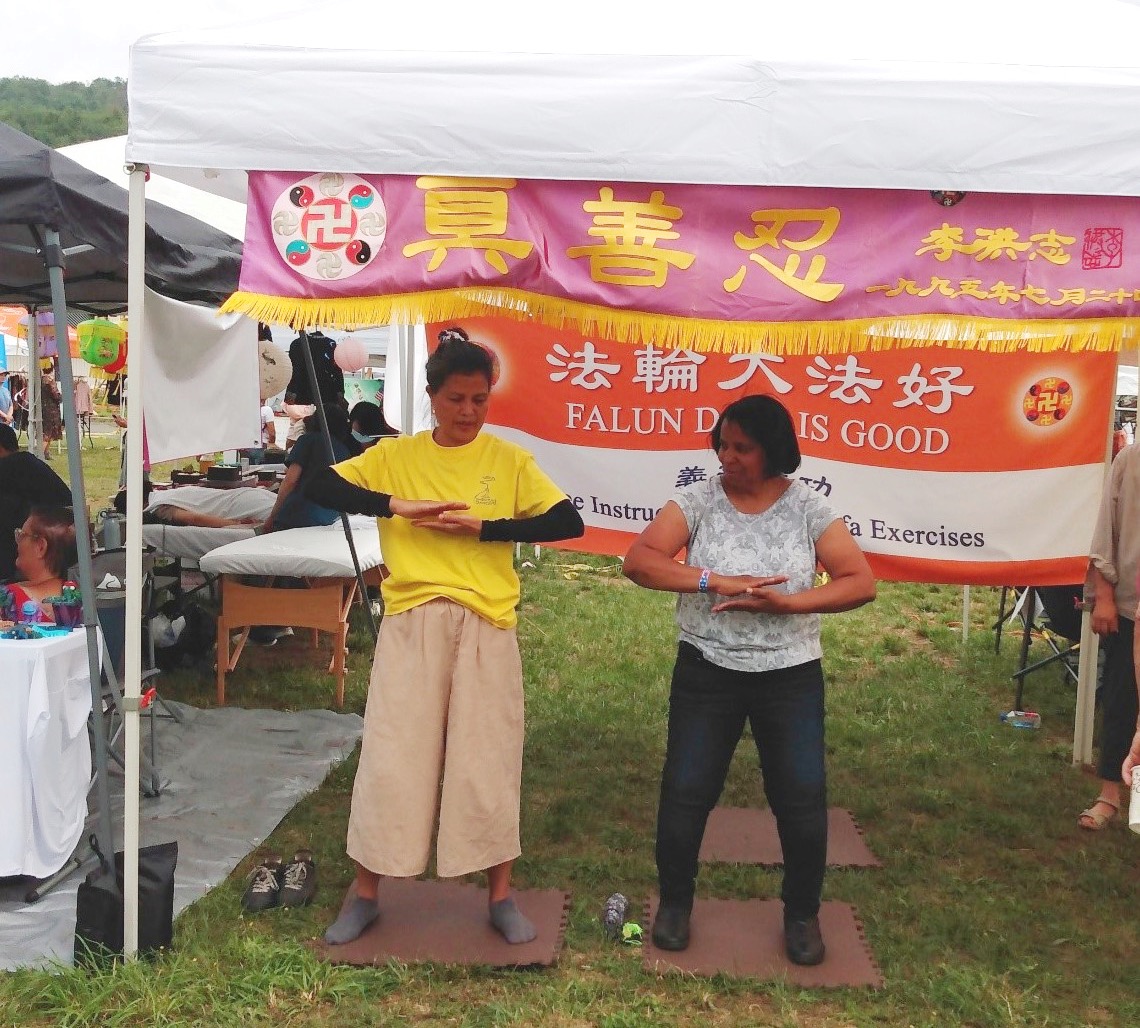 图6:琳恩女士在展位上和学员学炼功法