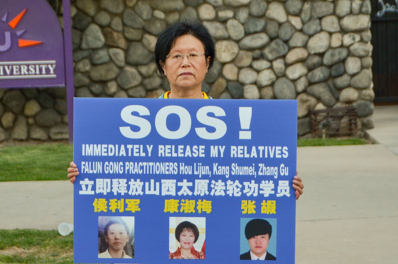 '图13:法轮功学员康女士手持亲人照片,呼吁营救被非法关押的亲人们。'