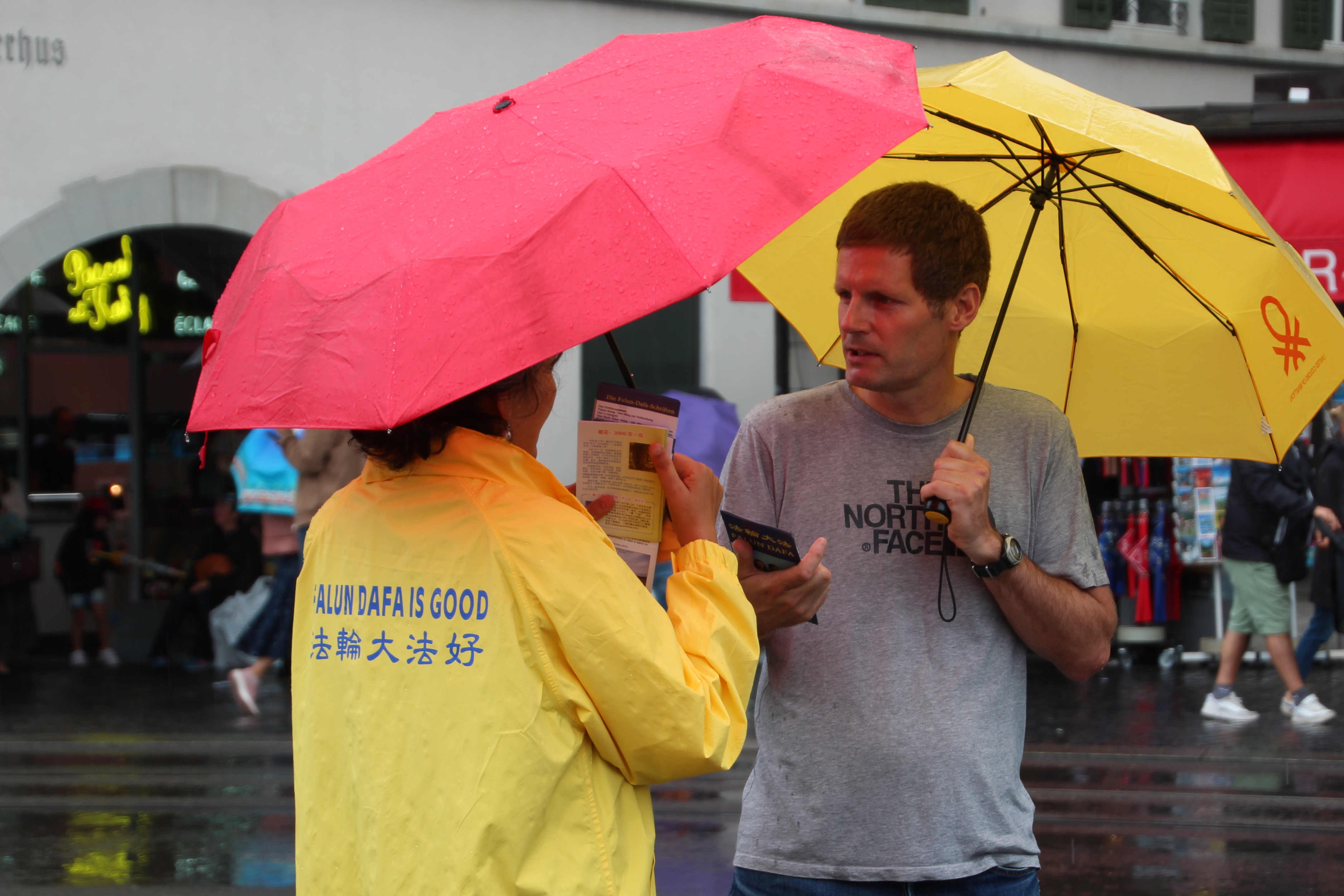 图3~4:人们在雨中和法轮功学员交谈,了解真相