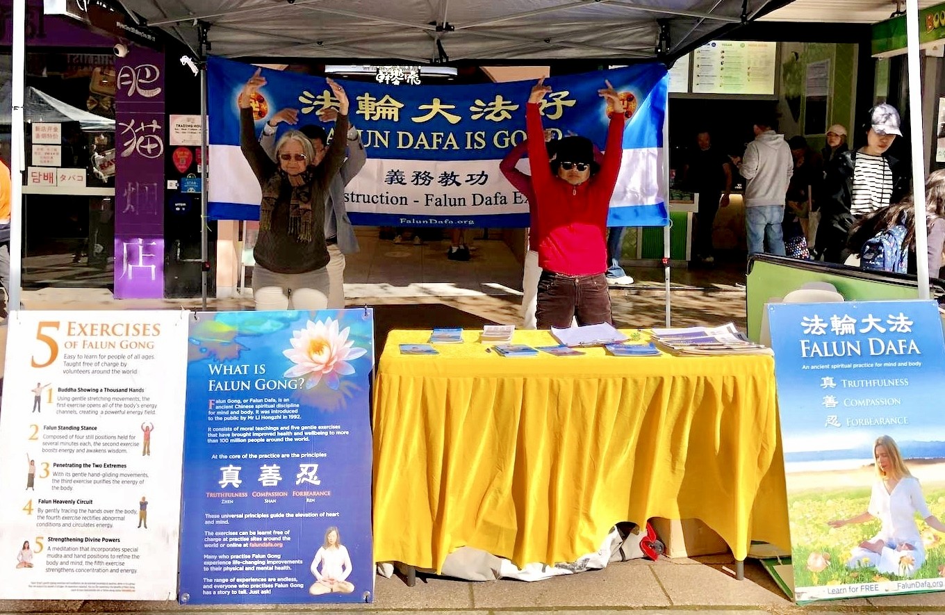 图4:法轮功学员在咨询展位上展示法轮功五套缓、慢、圆的祥和舒展的功法。