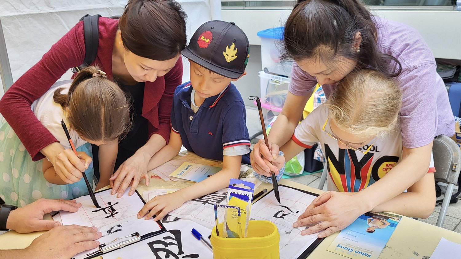 图6:法轮功展位用书法教授学习书写真、善、忍的活动吸引着孩子们,孩子们学习写字的同时知道了什么是真、善、忍的意义。