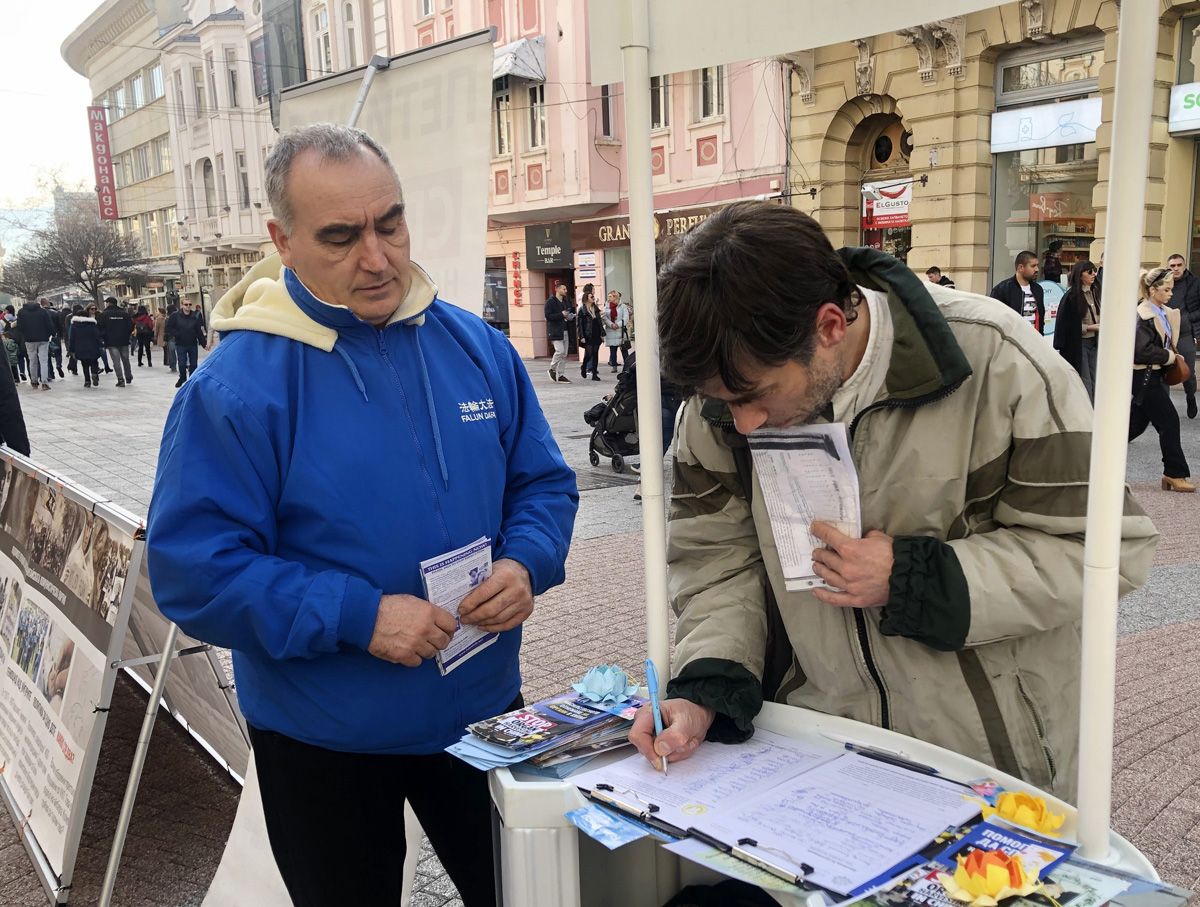 图6:一名男子在请愿书上签名后购买了一本《转法轮》,希望了解更多