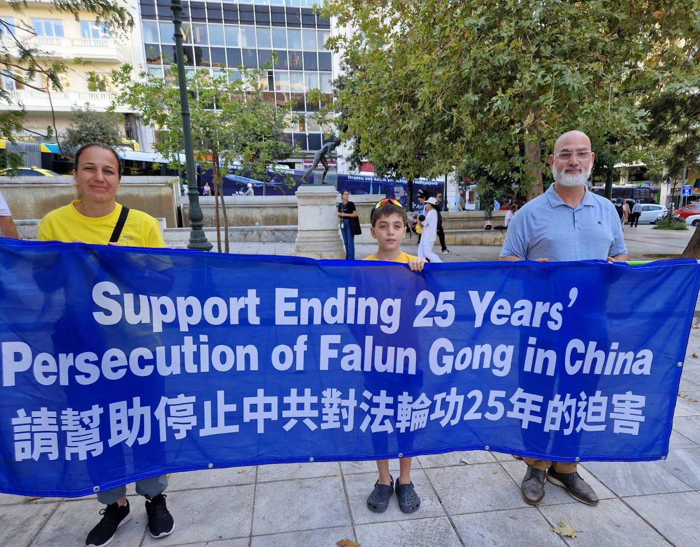 图12:朱莉亚一家举着横幅:“支持制止在中国对法轮功二十五年的迫害”。