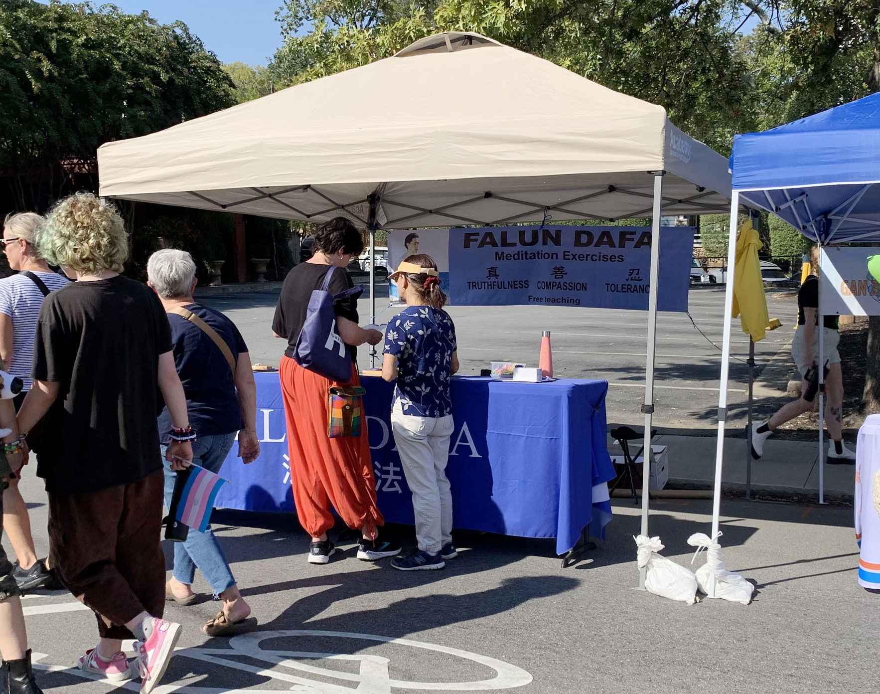 图:二零二四年十月十二日,法轮功学员参加美国南部阿肯色州小石城中城小山顶社区举办庆祝秋收的活动设立摊位。吸引许多人驻足,有的与学员交谈想了解更多关于法轮功的讯息。