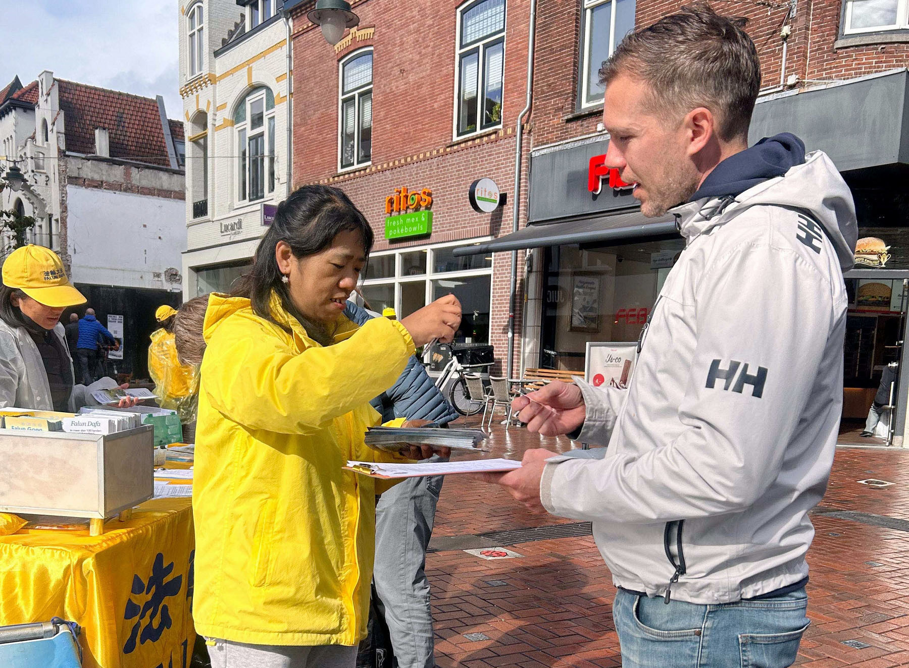 图13~15:学员们在雨中炼功讲真相,当地居民和游客由衷赞叹敬佩。