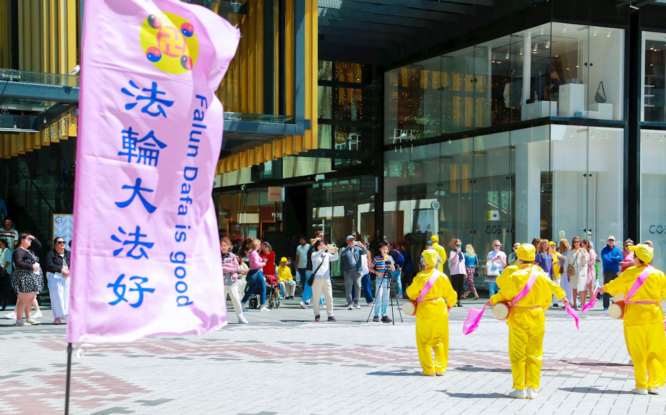 '图7~8:法轮功学员组成的腰鼓队在活动现场表演,人们驻足观看。'
