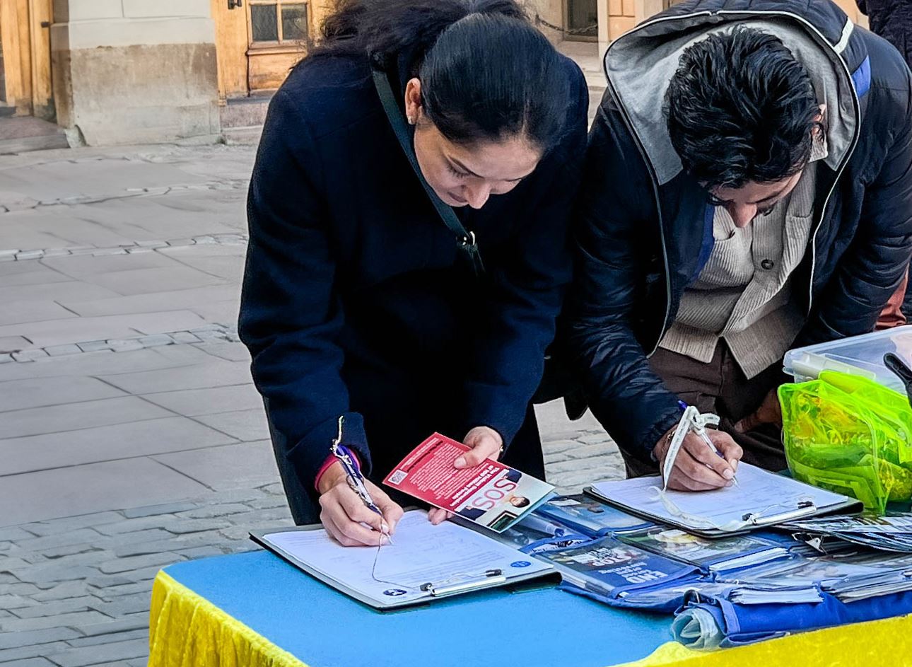 '图9~11:许多游客接到学员派送的真相传单后,在现场就开始阅读。明白真相的人主动签名支持法轮功学员反迫害。'