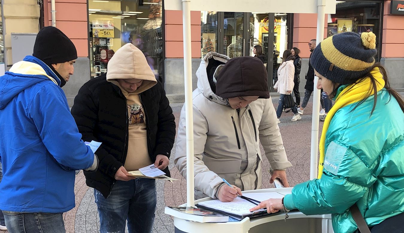 '图1:路人不惧严寒,纷纷驻足签名,以表示对法轮功的支持。'