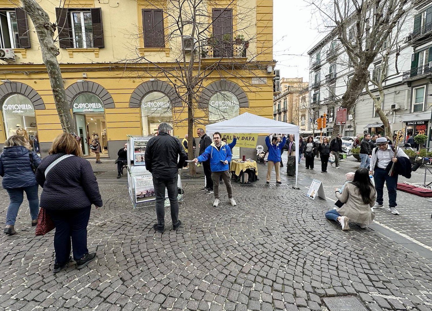 图1:三月二十四日,法轮功学员在那坡理(Napoli),繁华的佛梅罗(Vomero)中心地带的步行街举办讲真相活动。学员向市民展示法轮功功法。