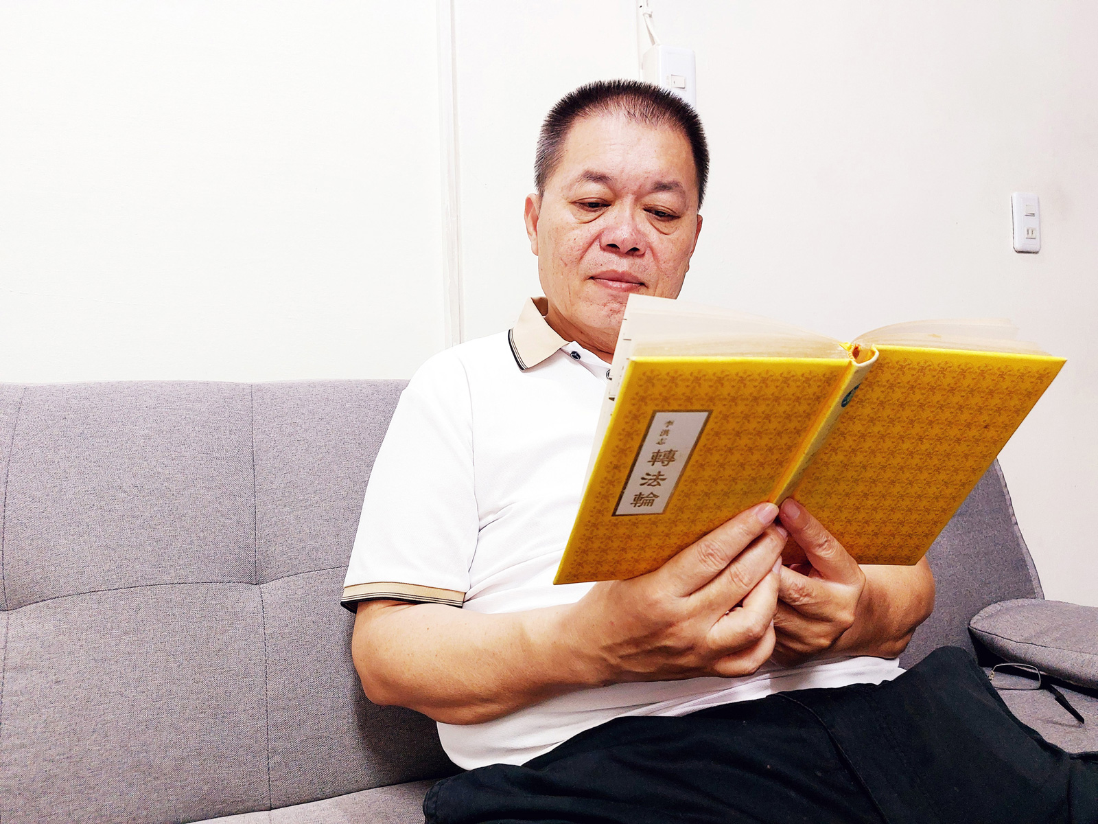 图1:忠勋正在阅读宝书《转法轮》。