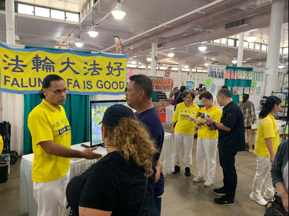 '图2:在真相展位前,法轮功学员向民众讲述法轮大法的真相和美好'