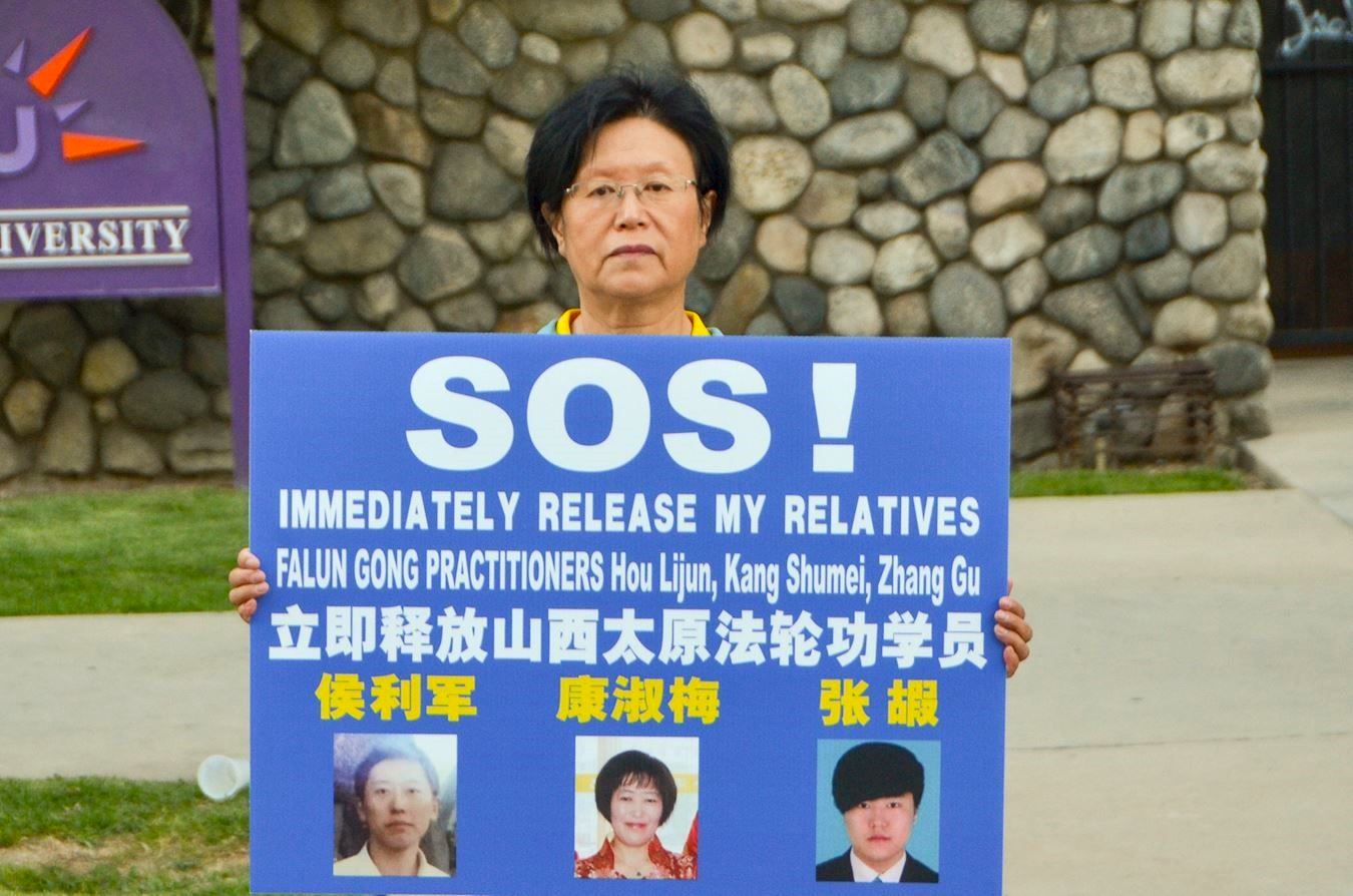 '图9:康女士手持亲人照片,呼吁营救亲人们。'