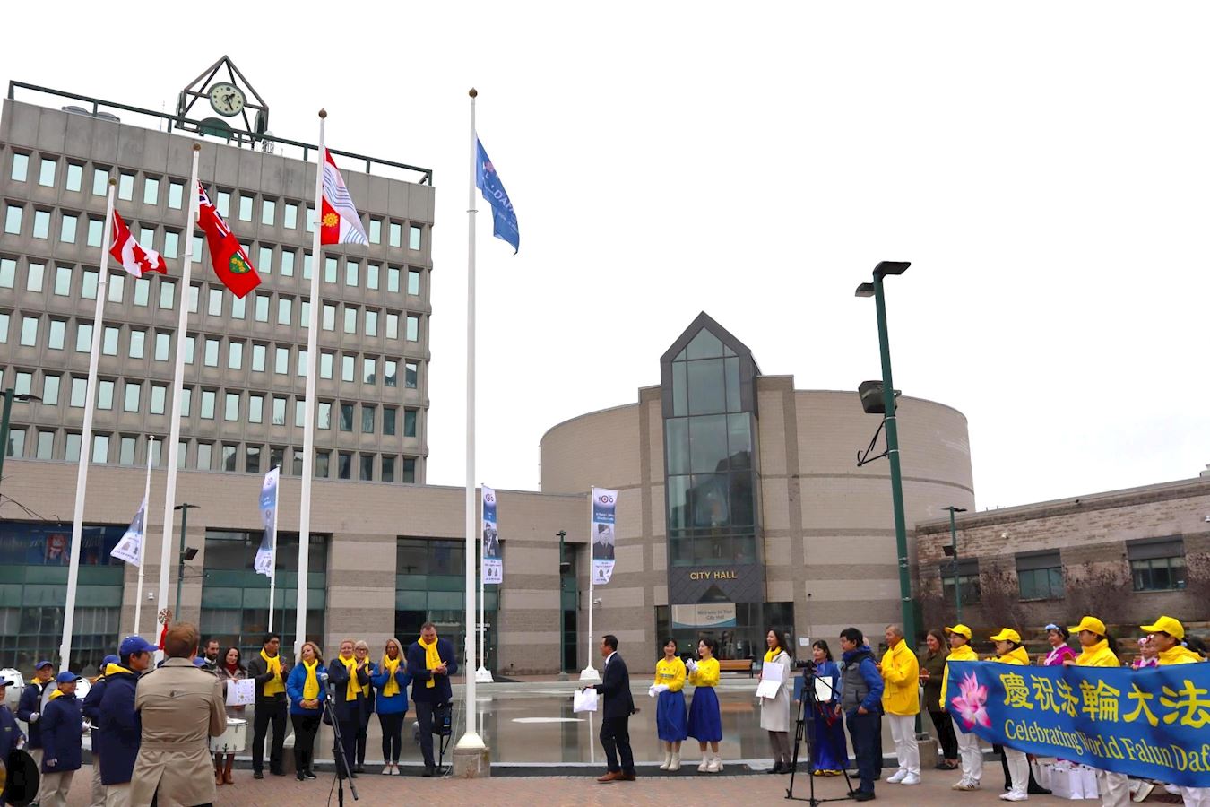 '图1~2:庆祝世界法轮大法日的旗帜今年首场在巴里市(Barrie)升起。'