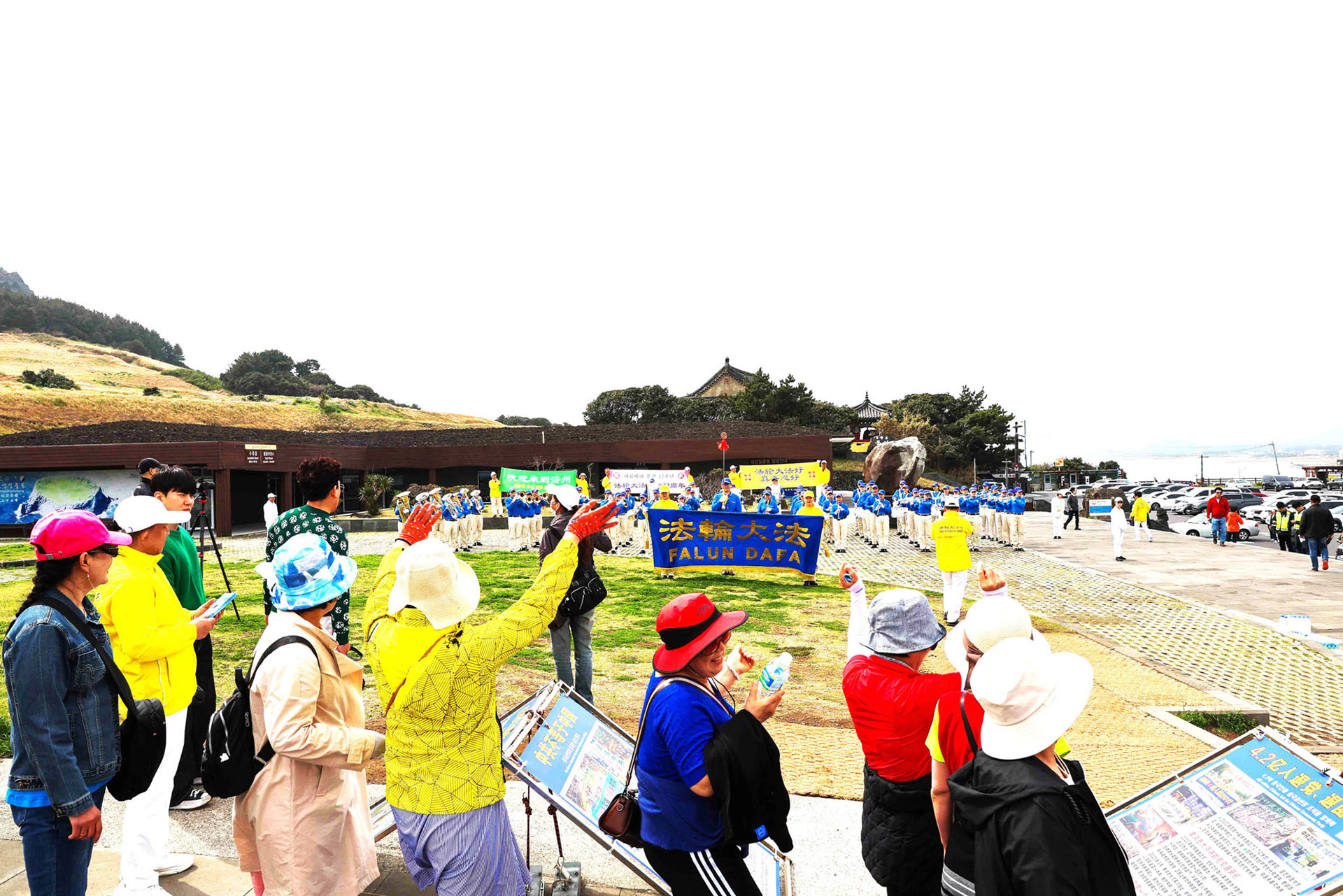 图8:在城山日出峰法轮功真相展位附近,中国游客向正在演出的天国乐团挥手致意。