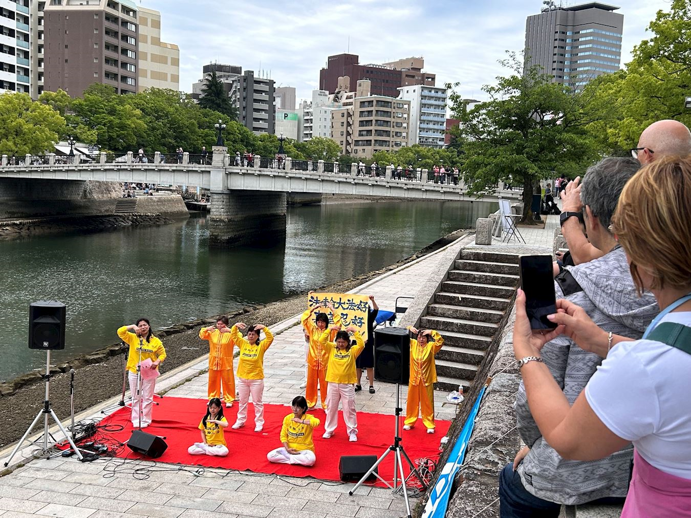 '图7:法轮功学员在演示五套功法时,观众纷纷拍照录像'