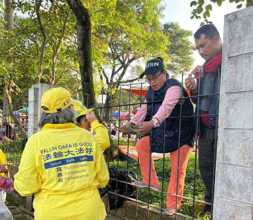 图10:燕蒂和她的丈夫隔着栅栏向学员拿取传单后表示,非常认同法轮功,他们想学炼功法。