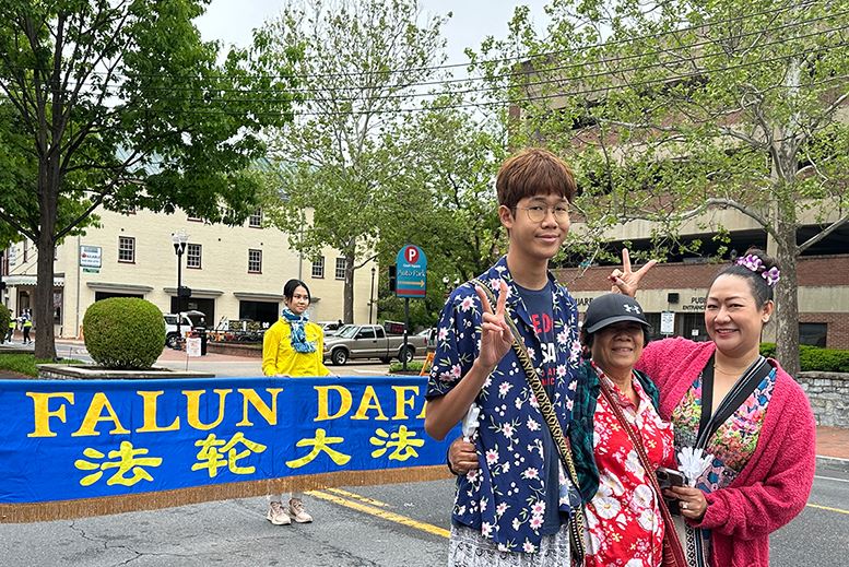 '图6:来自泰国的游客詹恩(右一)和母亲及儿子在法轮大法横幅前合影。'