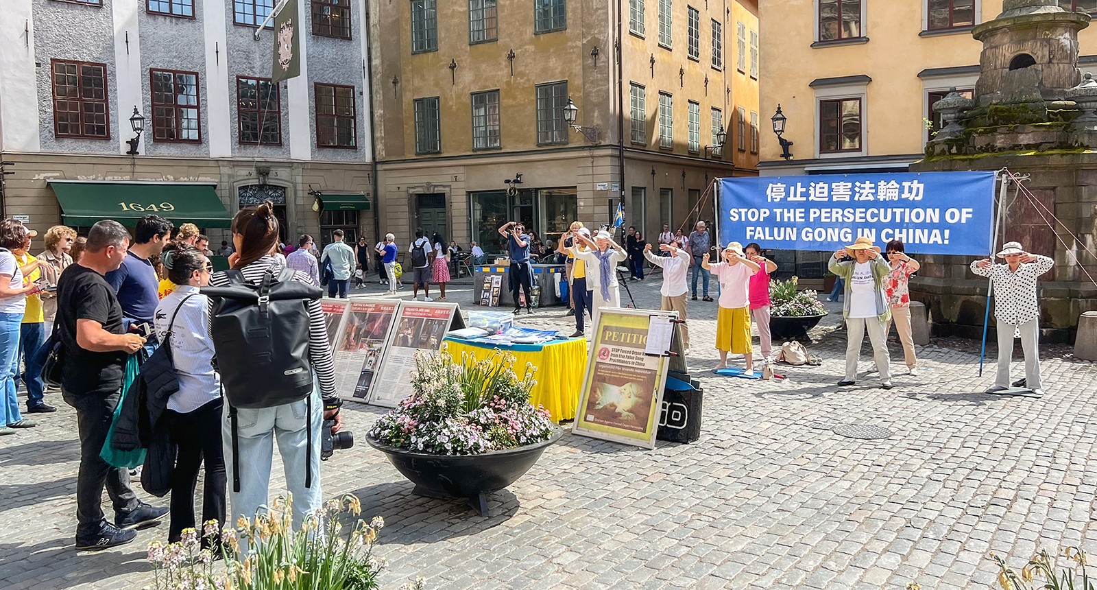 图1:二零二四年五月份每周五和周六,法轮功学员在斯德哥尔摩诺贝尔博物馆前设立真相展位。学员向市民演示祥和优美的五套功法,吸引了许多人驻足观看了解真相。