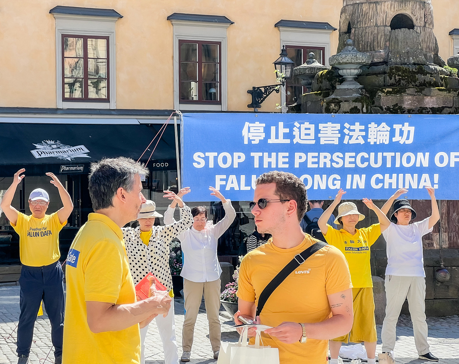 图3~5:法轮功学员向来自世界各地的游客介绍法轮功,揭露中共活摘法轮功学员器官的事实真相。